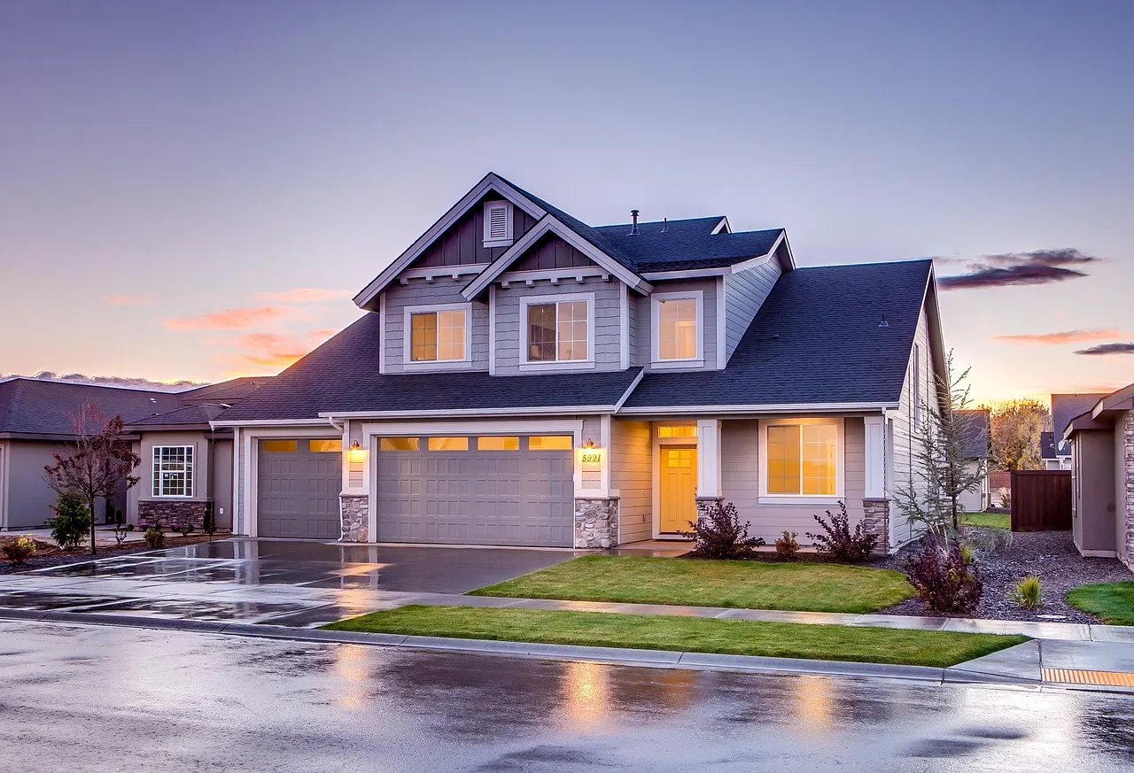 A two-storey home in a residential neighbourhood at dusk, lights on inside